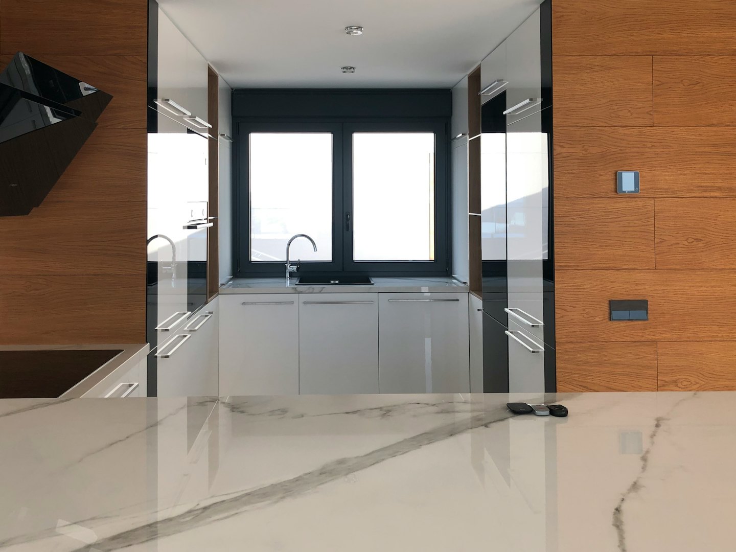 Modern kitchen with white cabinets and a marble countertop.