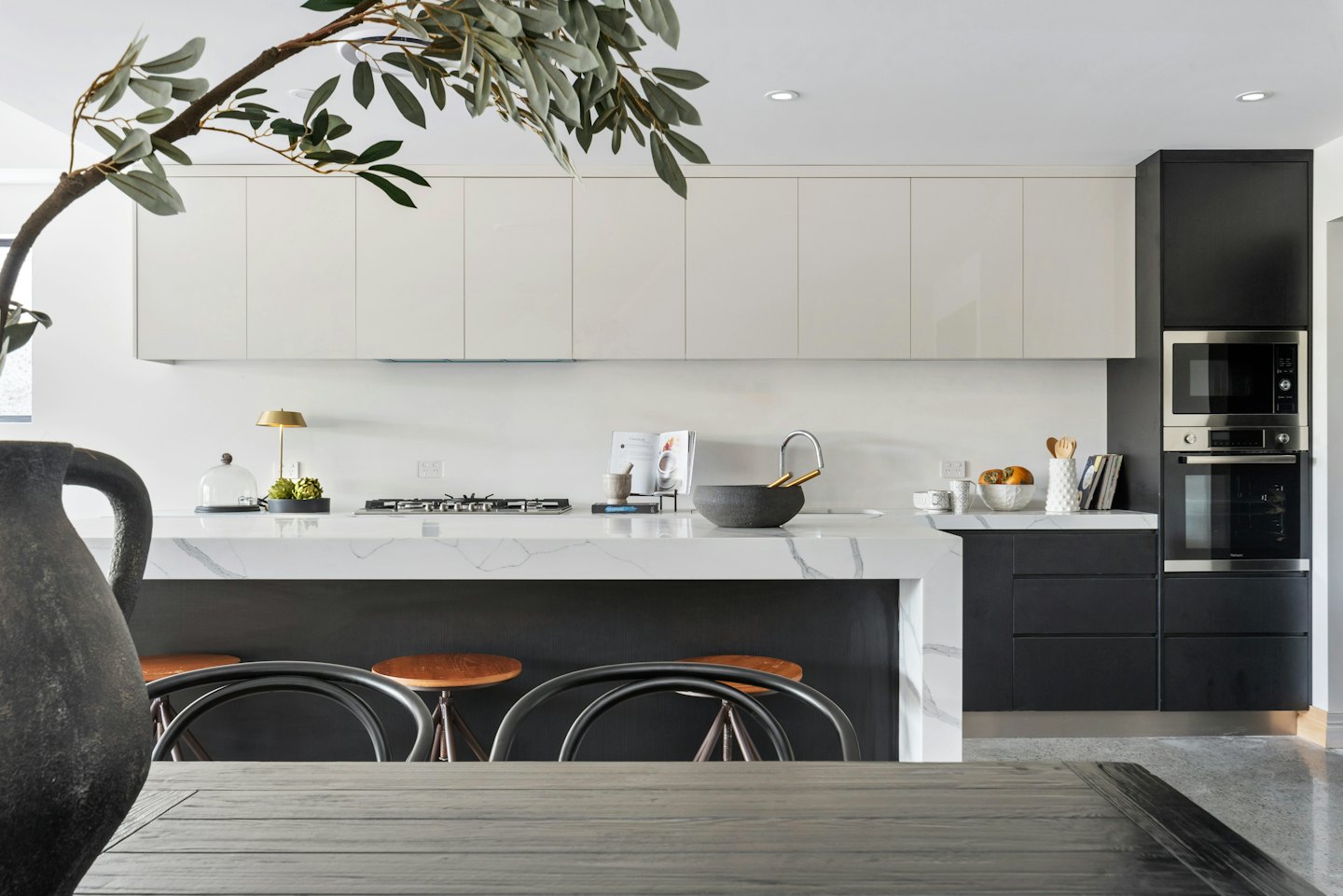 Modern kitchen with marble island and dark grey cabinets.